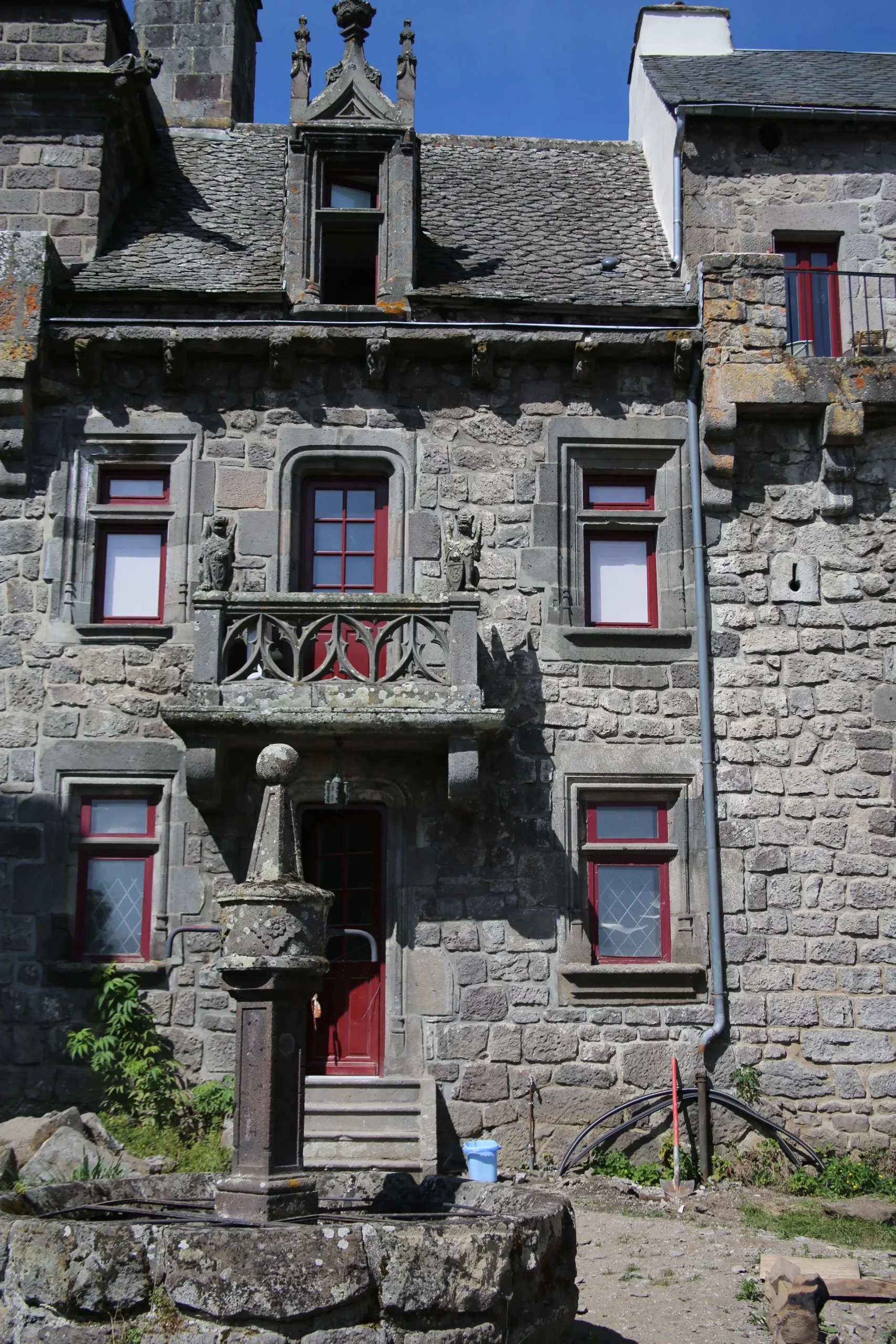 Historic stone house with ornate balcony and well