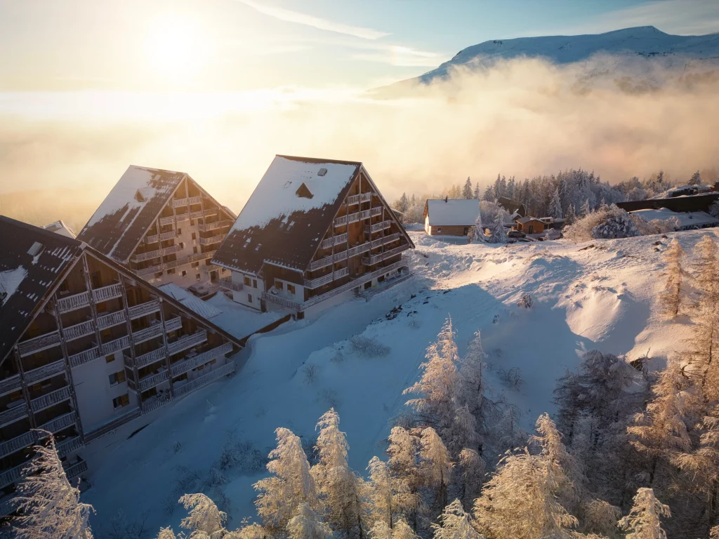 Snow-covered mountain chalets at sunrise with mist