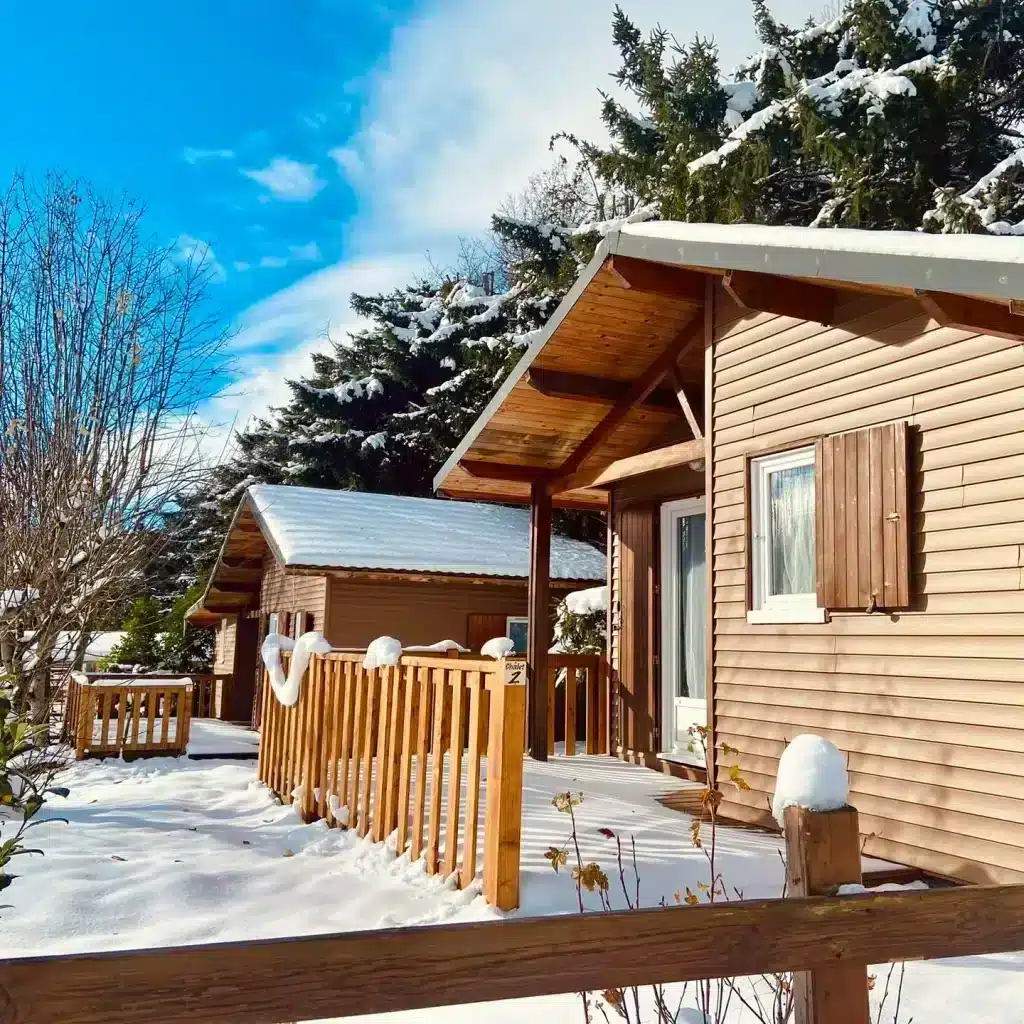 Snow-covered wooden cabins under bright blue sky