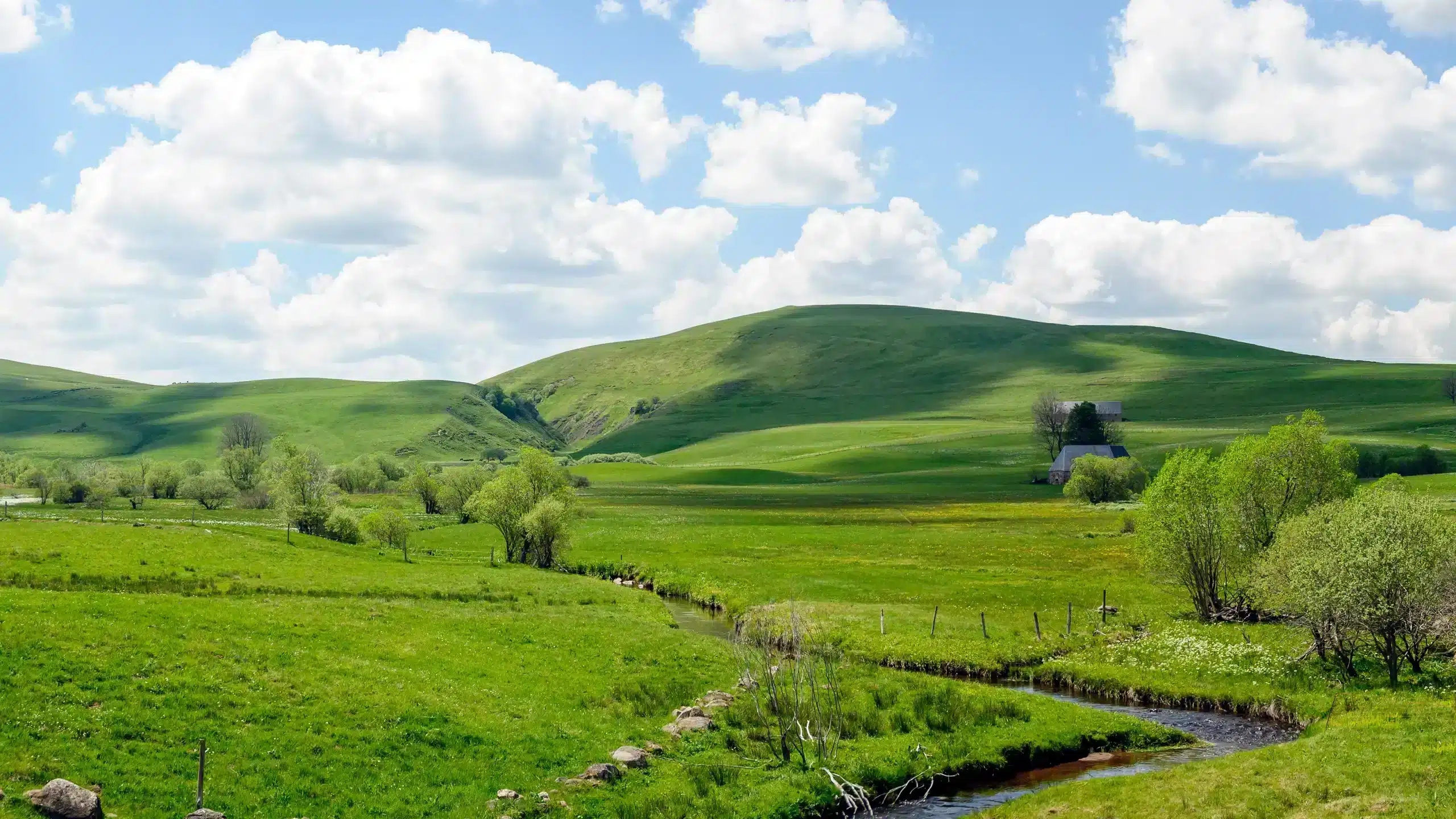 Rolling green hills with farmhouse and stream