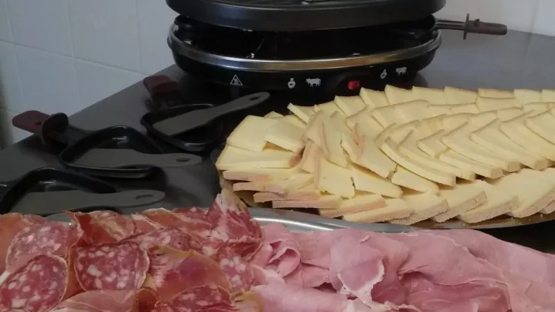 Raclette grill with sliced cheese and cured meats
