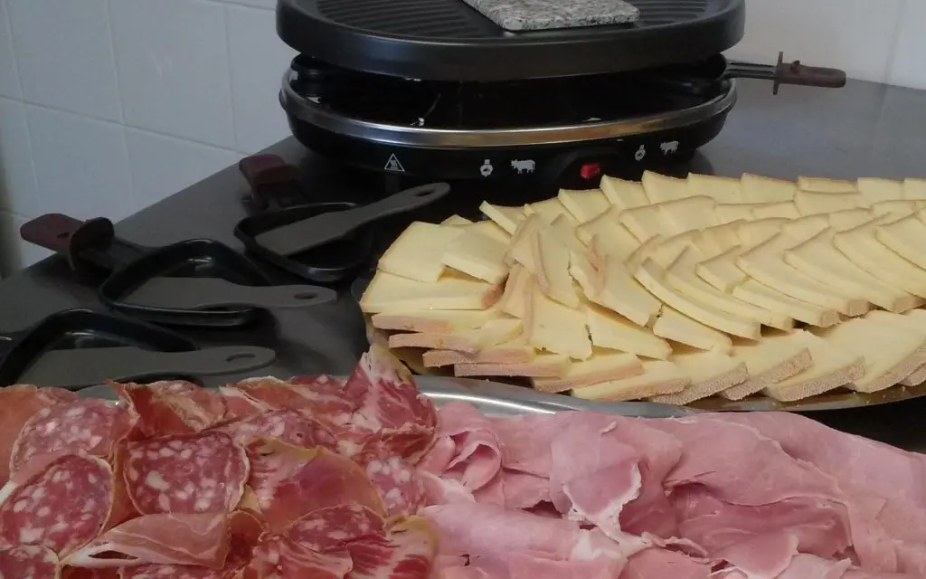 Raclette grill with sliced cheese and cured meats