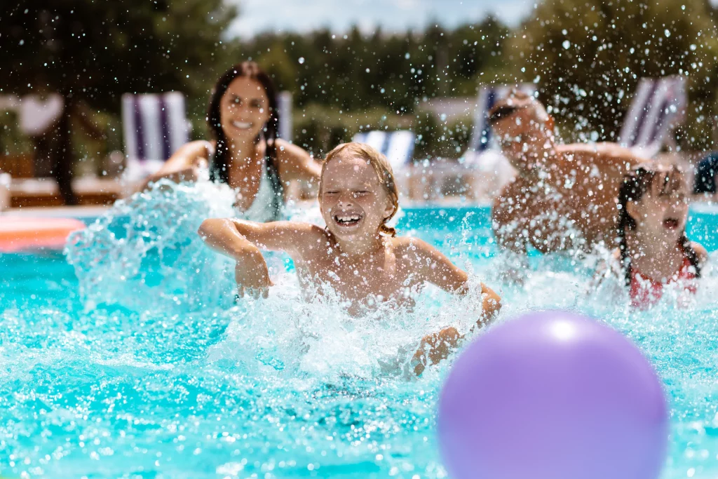 Family splashing and playing in outdoor swimming pool