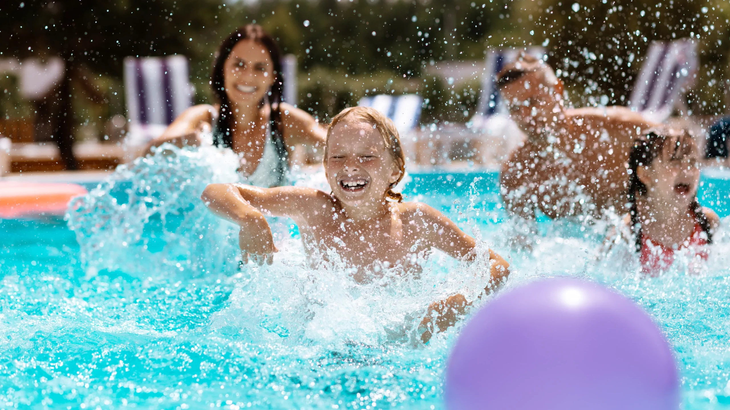 Family splashing and playing in outdoor swimming pool