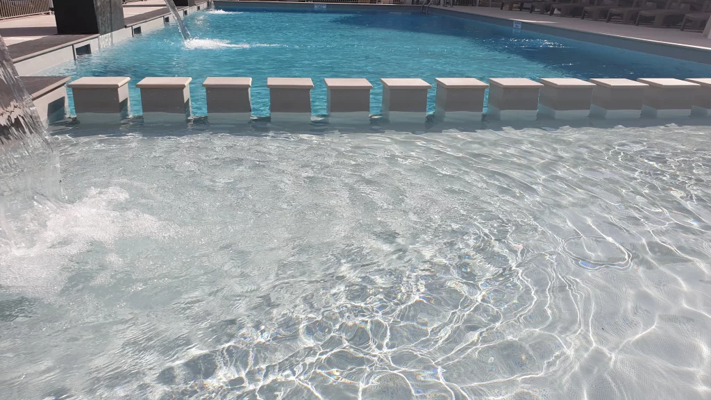 Resort swimming pool with waterfall and submerged stools