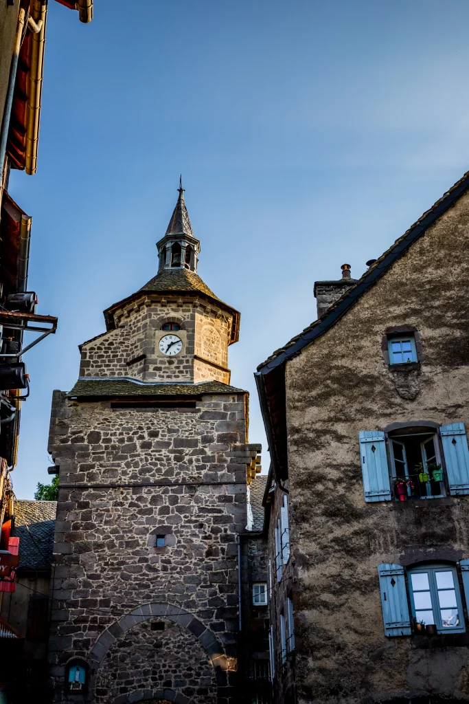 Stone clock tower between old village buildings