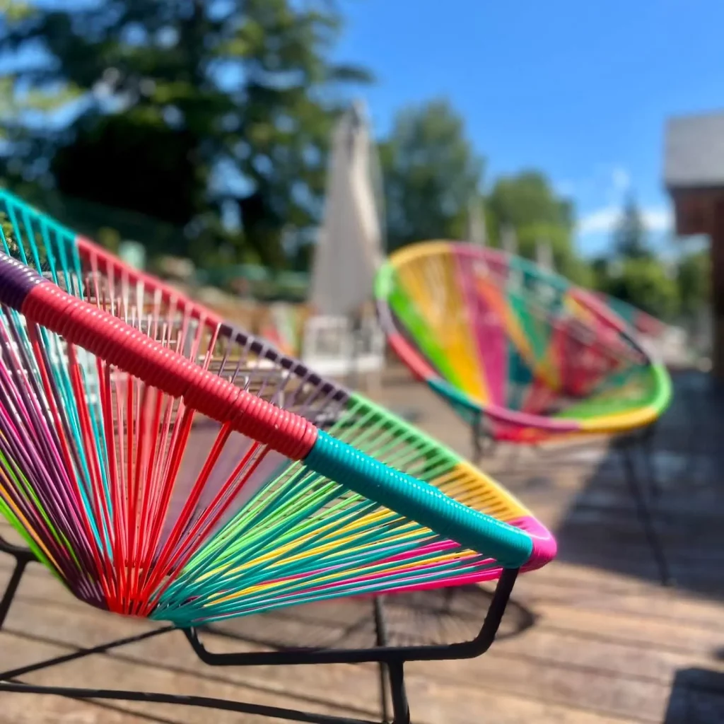 Colorful woven patio chairs on sunny wooden deck