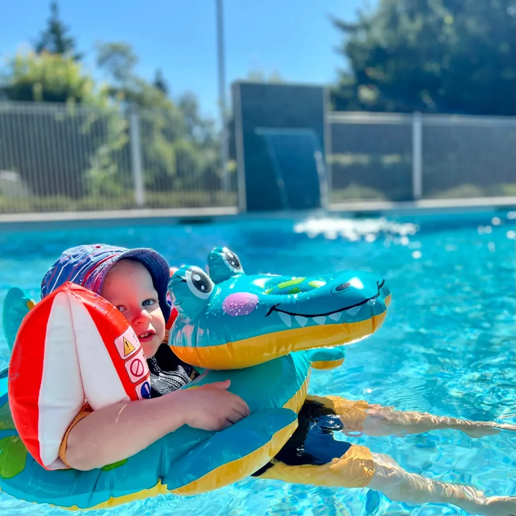 Toddler with inflatable crocodile float in pool