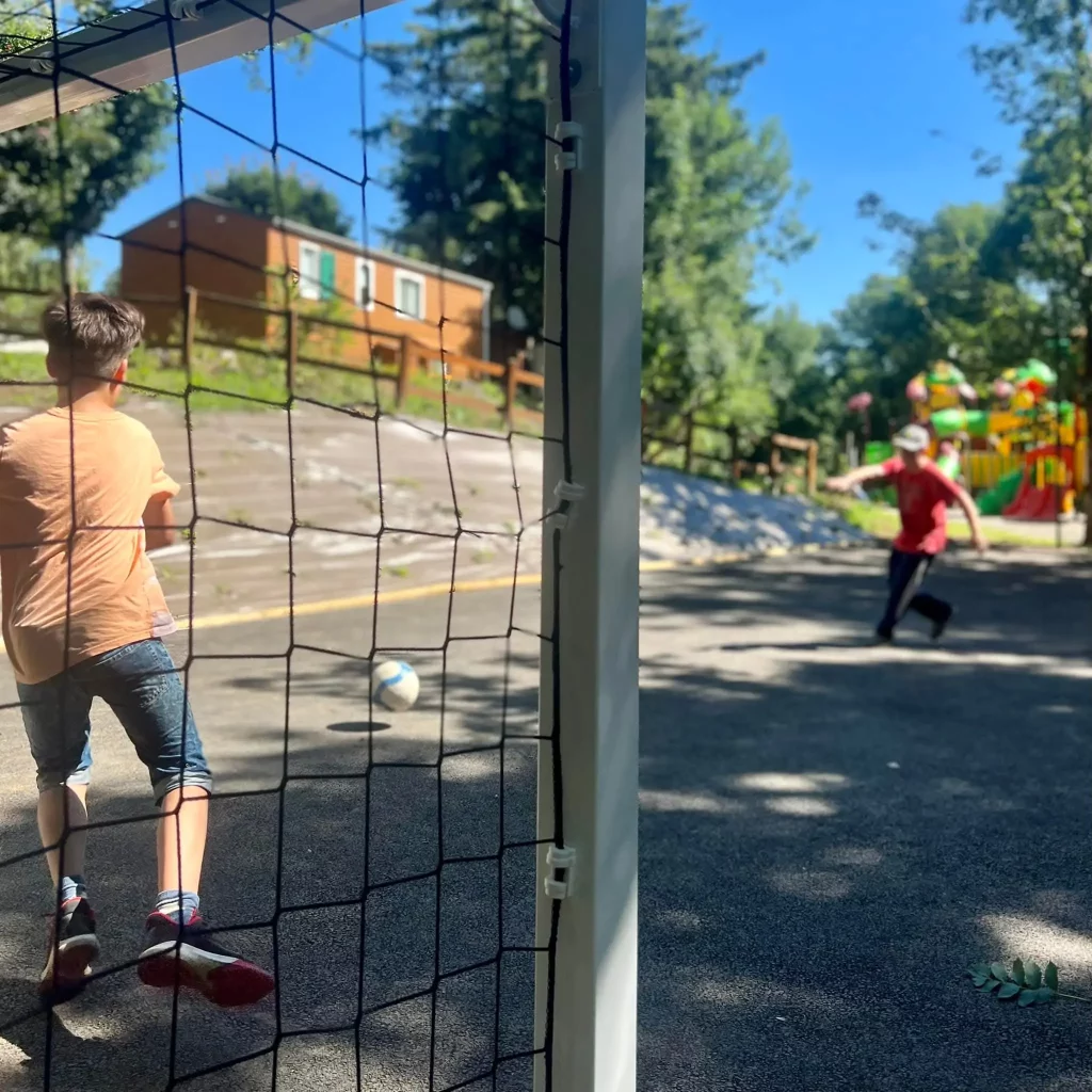 Children playing soccer near playground on sunny day