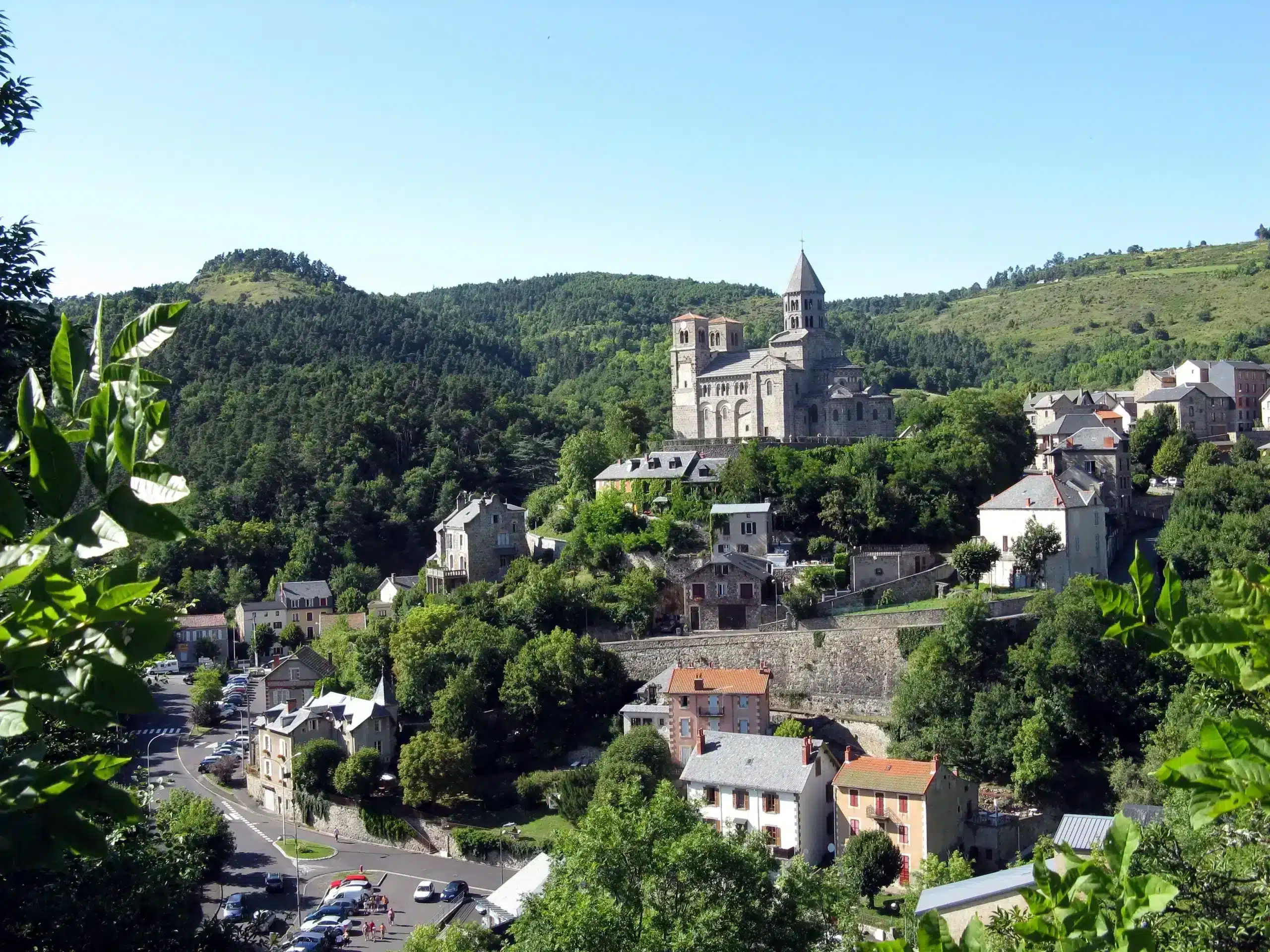 Hillside village with stone church and green forest